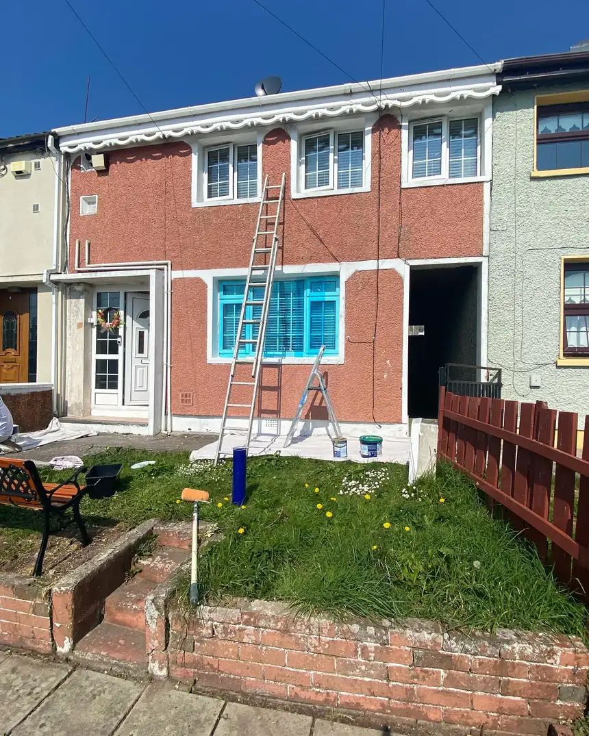 Before: a terraced house in its old red render with ladders up