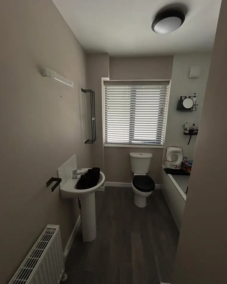 Bathroom in a warm grey with white sanitary ware and a white blind