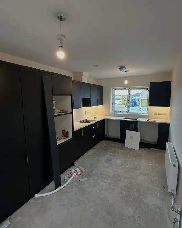 New build kitchen with dark units and freshly painted walls and ceiling