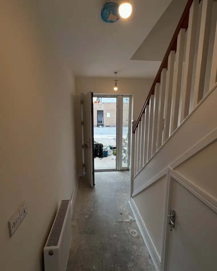 New build hall with white panelling and a freshly painted stairs