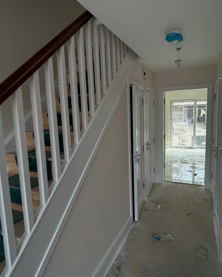 New build stairs with white spindles and a timber handrail, before the floors go down