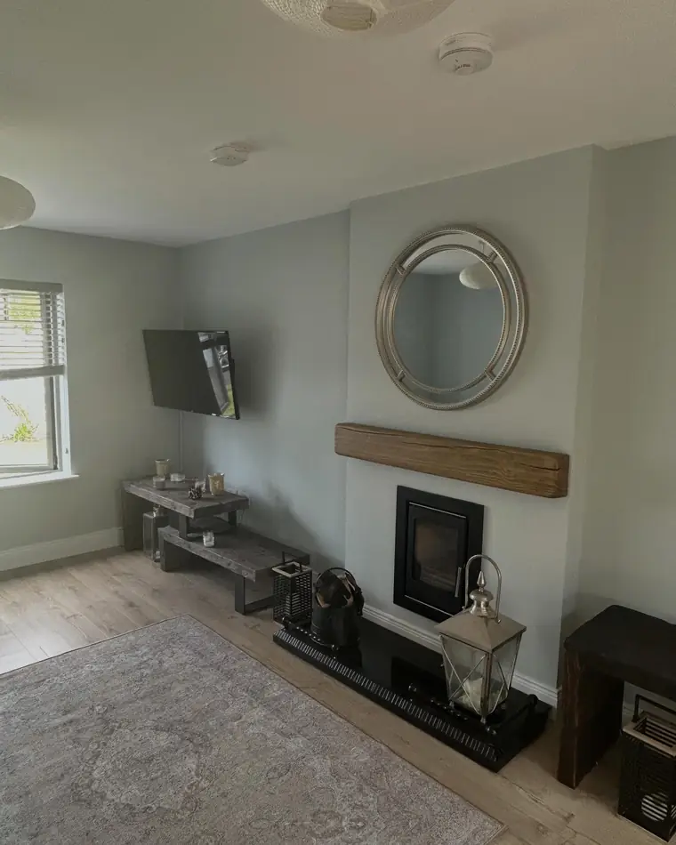Front room in a soft neutral with a fireplace and a round mirror