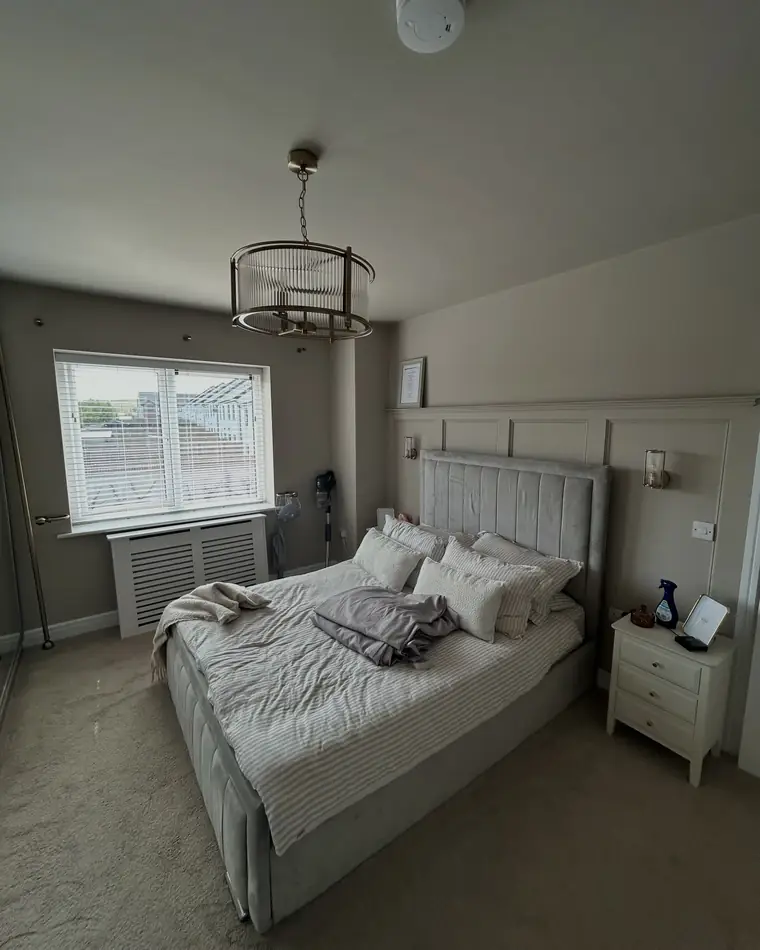 Bedroom finished in a warm grey with white woodwork and the bed made up