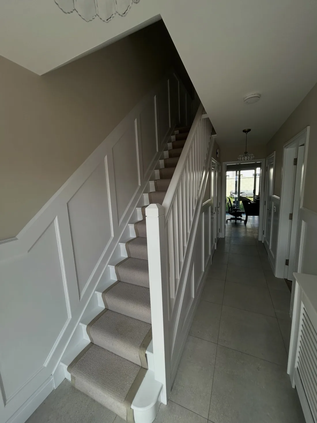 Hall and stairs painted by Robbie, with fresh white wall panelling and a soft grey wall above