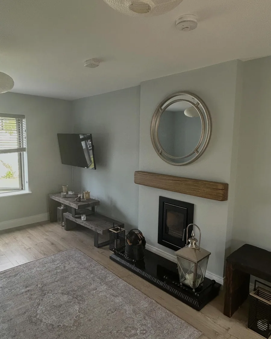 Front room repainted in a soft neutral, with a fireplace and a round mirror