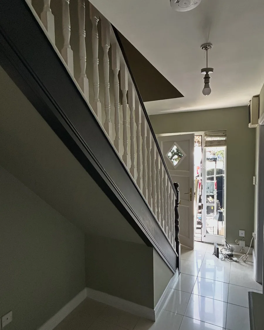 Hall and stairs with the stringer painted a deep olive and spindles in white